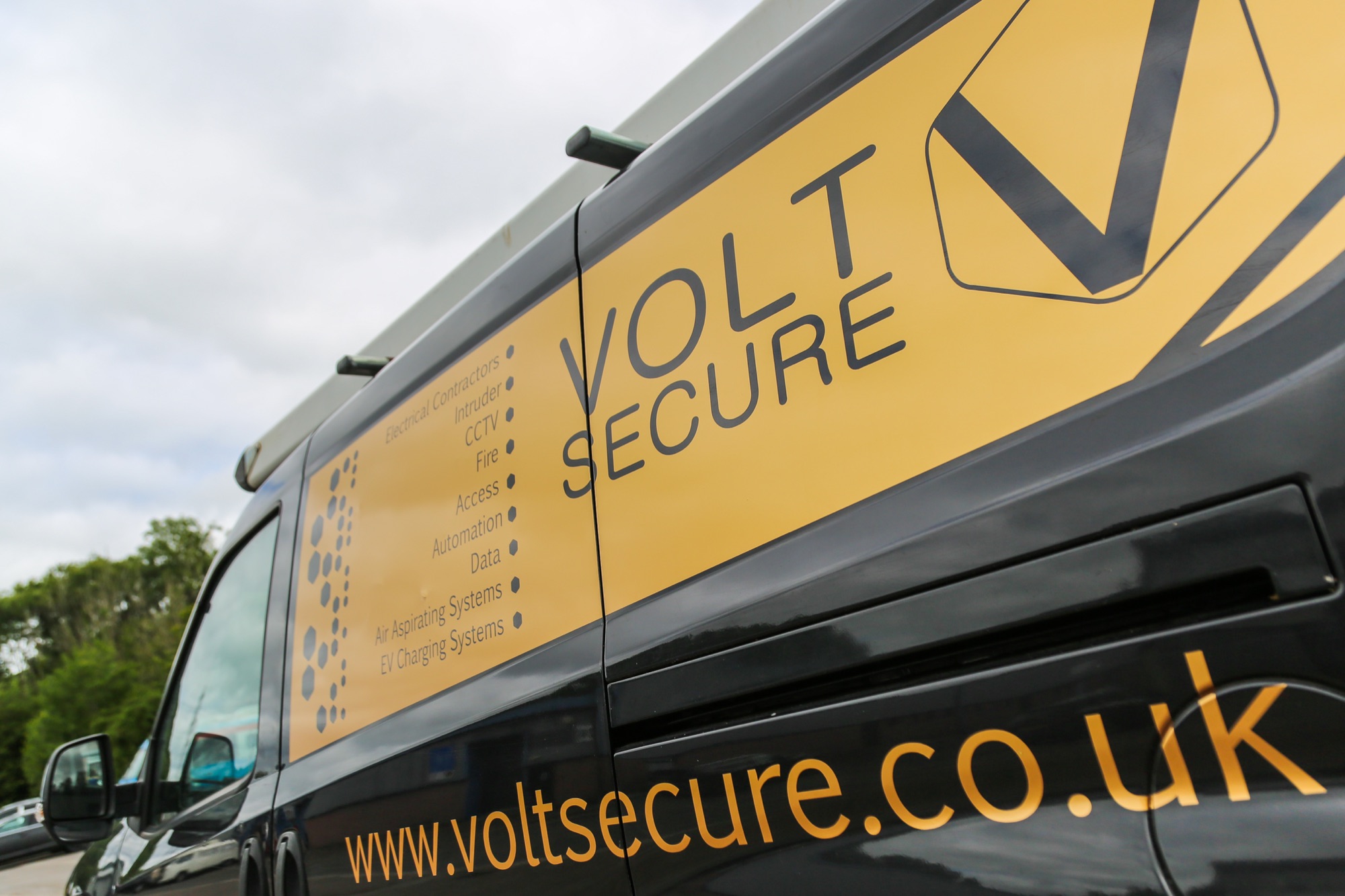 VoltSecure-liveried van side panel listing every discipline: electrical, intruder, CCTV, fire, access, automation, data, air aspirating systems, EV charging